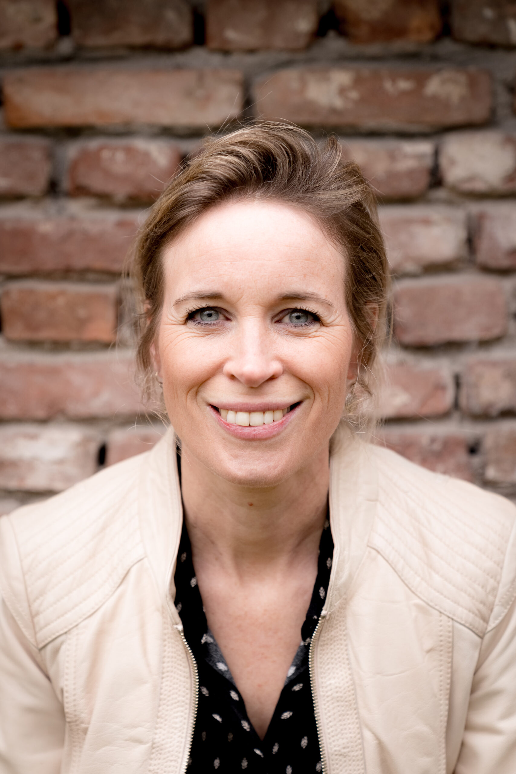 Nienke Nederveen tegen bakstenen muur, warme uitstraling